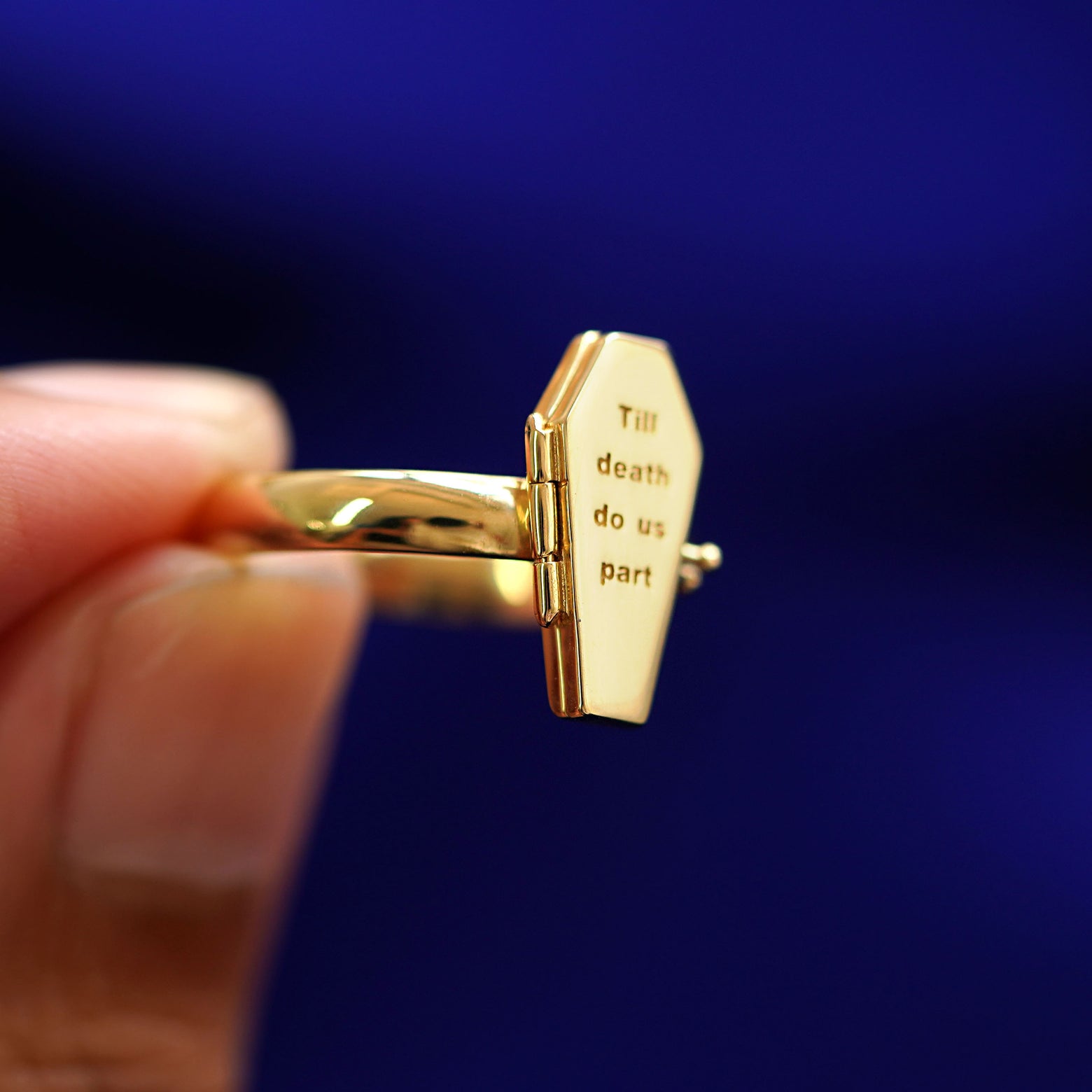 A model holding a Coffin Ring tilted to show the hinge on the coffin