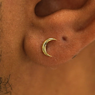 Close up view of a model's ear wearing a 14k gold Moon Earring