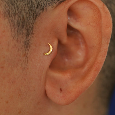 A model's ear wearing a 14k yellow gold Moon Flatback in a tragus piercing