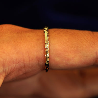 Side view of a Curvy Hammered Band on a model's finger