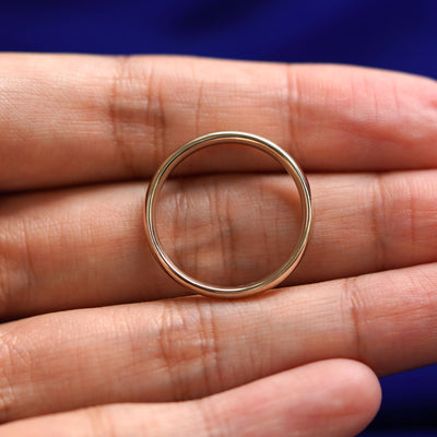 A yellow gold Curvy Mirror Band in a model's hand showing the thickness of the band