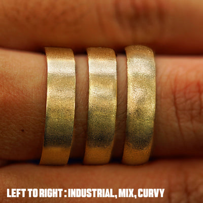 Close up view of a model's fingers wearing an Industrial Band Mix Band and Curvy band all in yellow gold