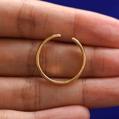 A yellow gold Open Curvy Band in a model's hand showing the thickness of the band