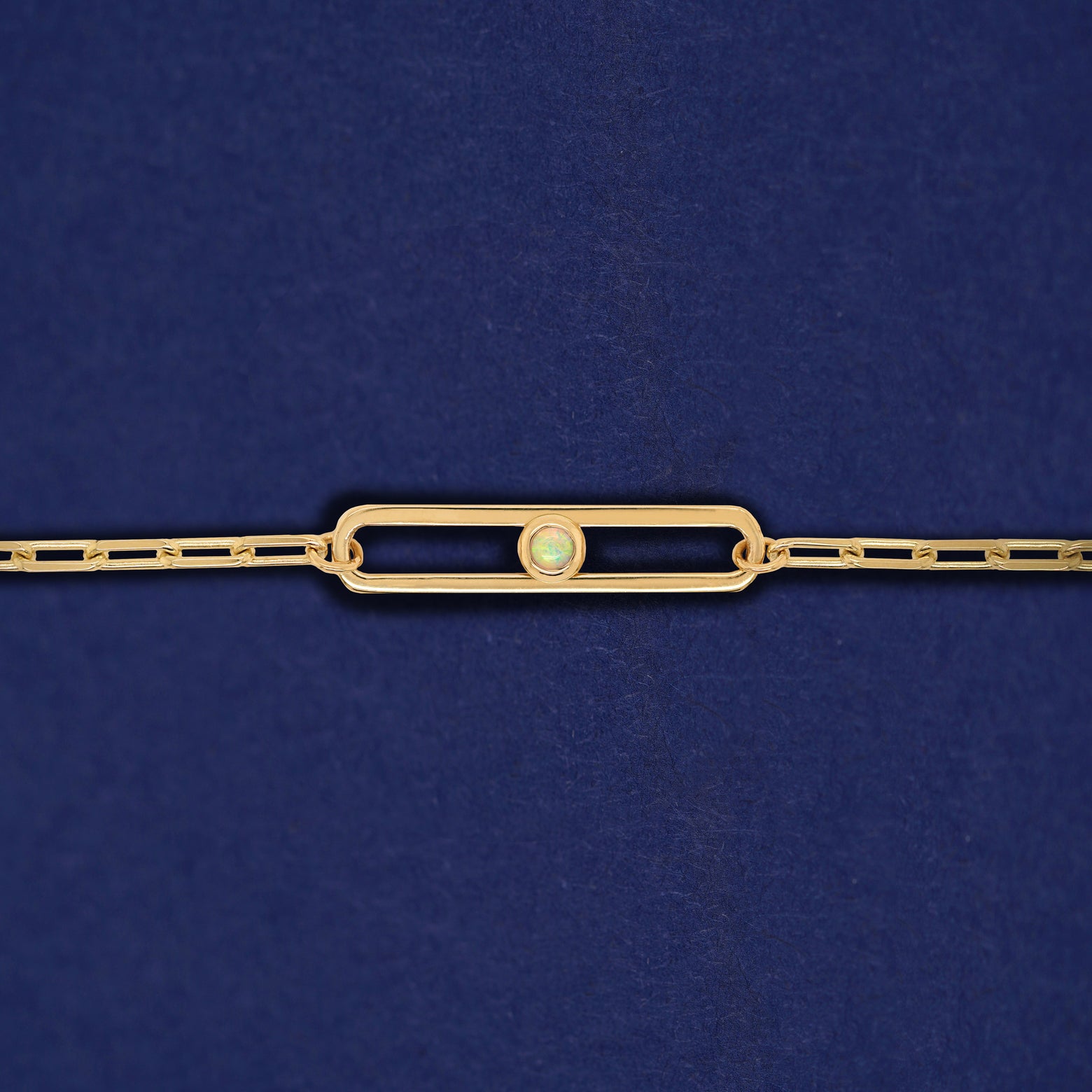 A yellow gold elongated open oval link with a single bezel set Opal inside on a 14k gold Butch chain bracelet