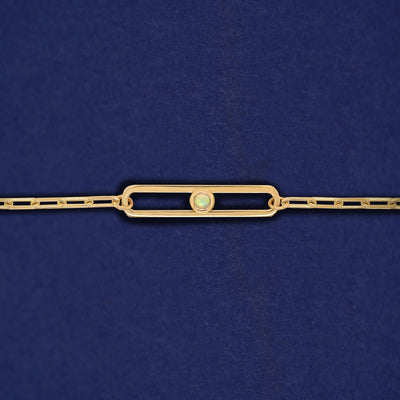 A yellow gold elongated open oval link with a single bezel set Opal inside on a 14k gold Butch chain bracelet