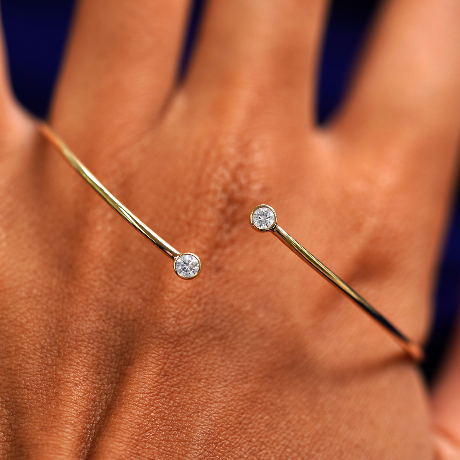 A solid gold Diamond Bypass Bracelet resting on the back of a model's hand