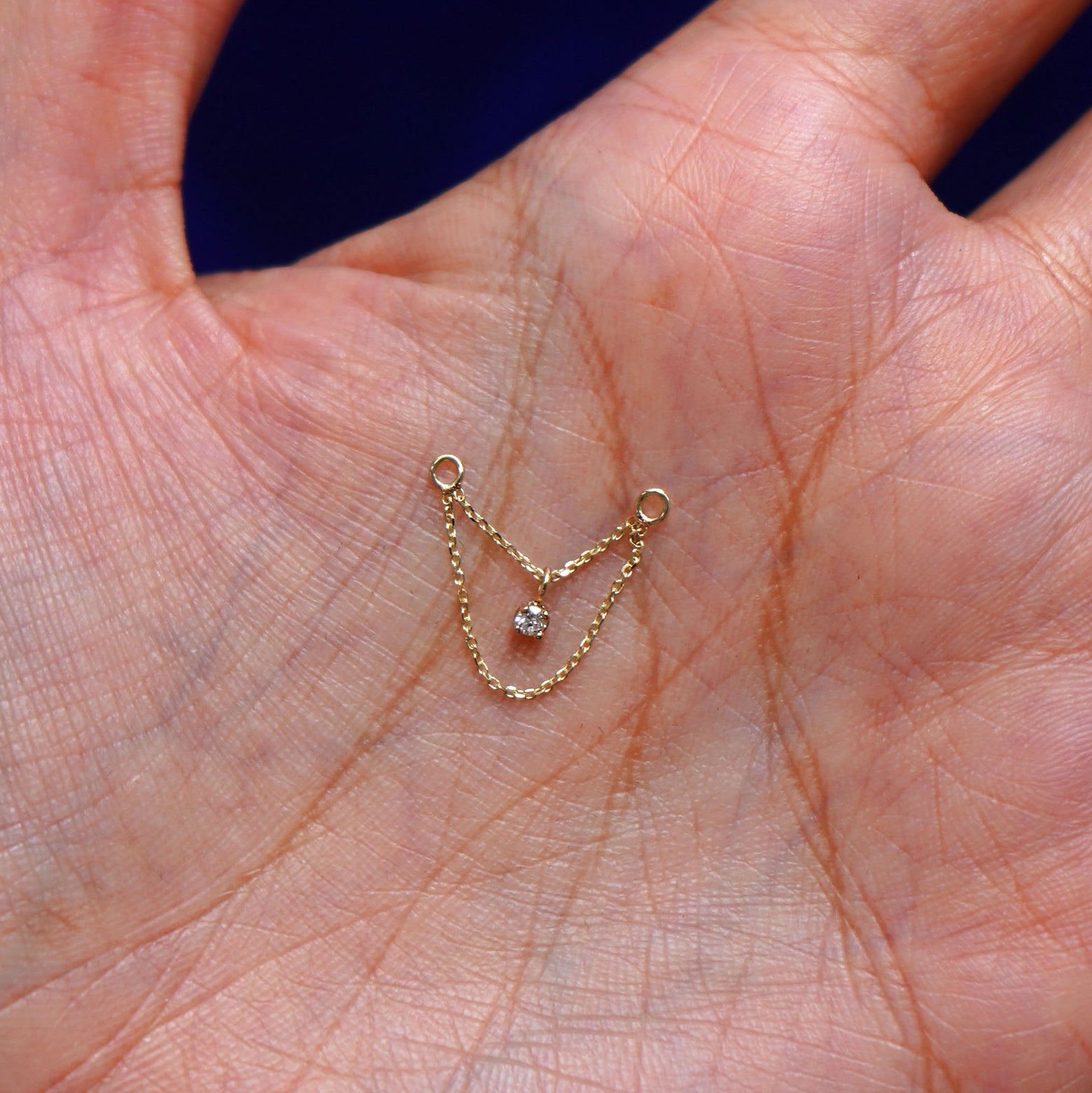 A solid 14k yellow gold Diamond Cable Chain Connector sitting in a model's hand