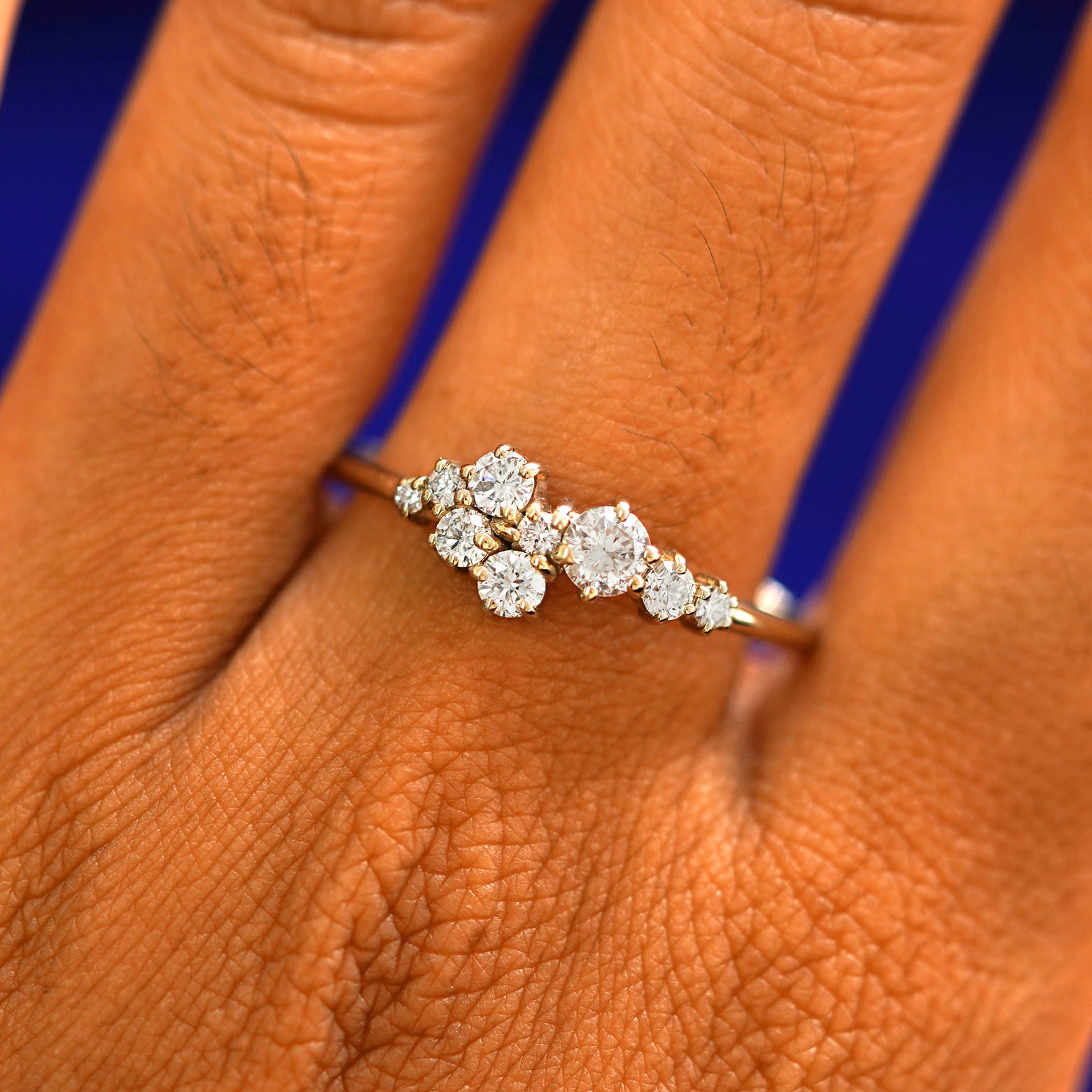 Close up view of a model's hand wearing a solid gold Diamond Cluster Ring