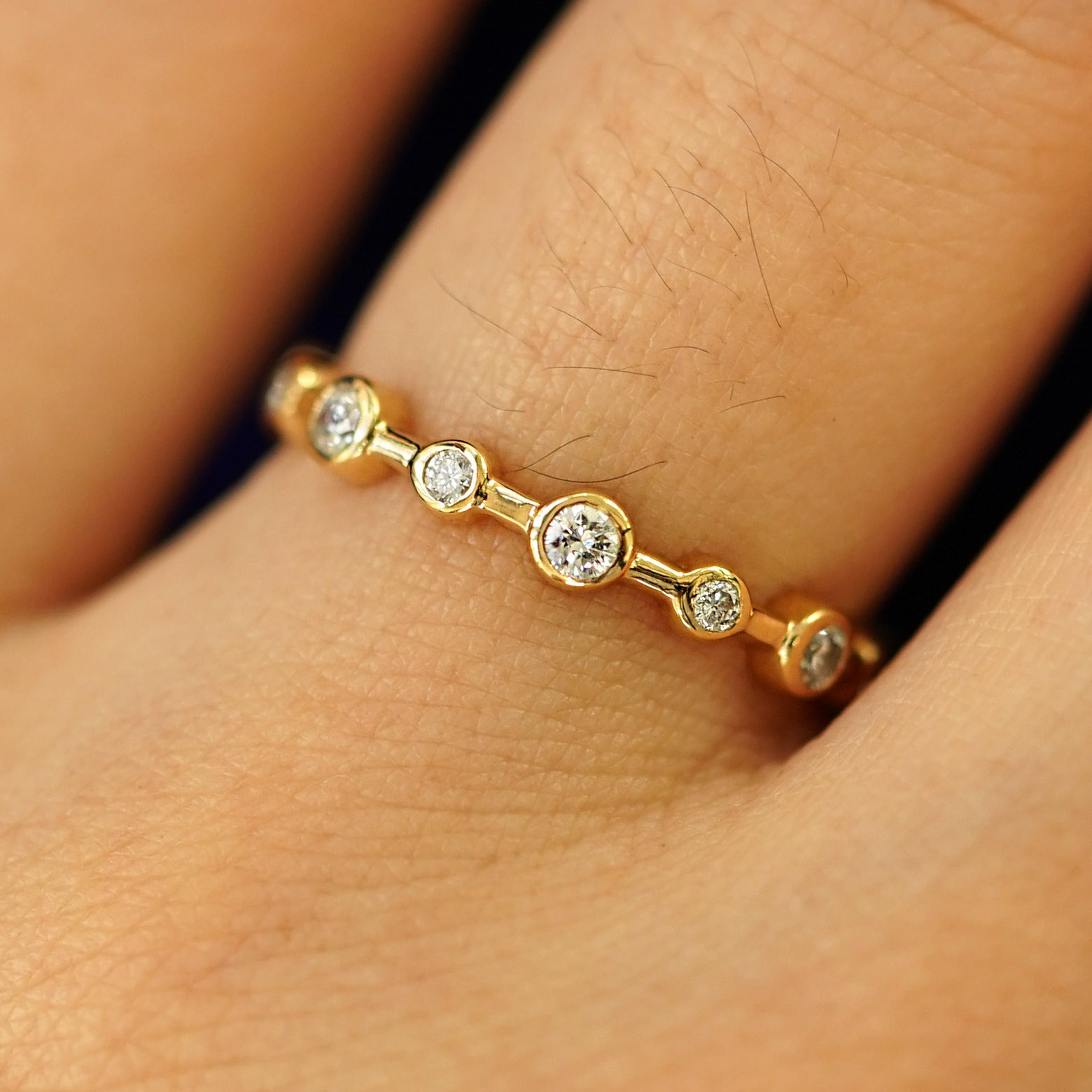 Close up view of a model's hand wearing a 14k yellow gold Infinity Diamond Ring