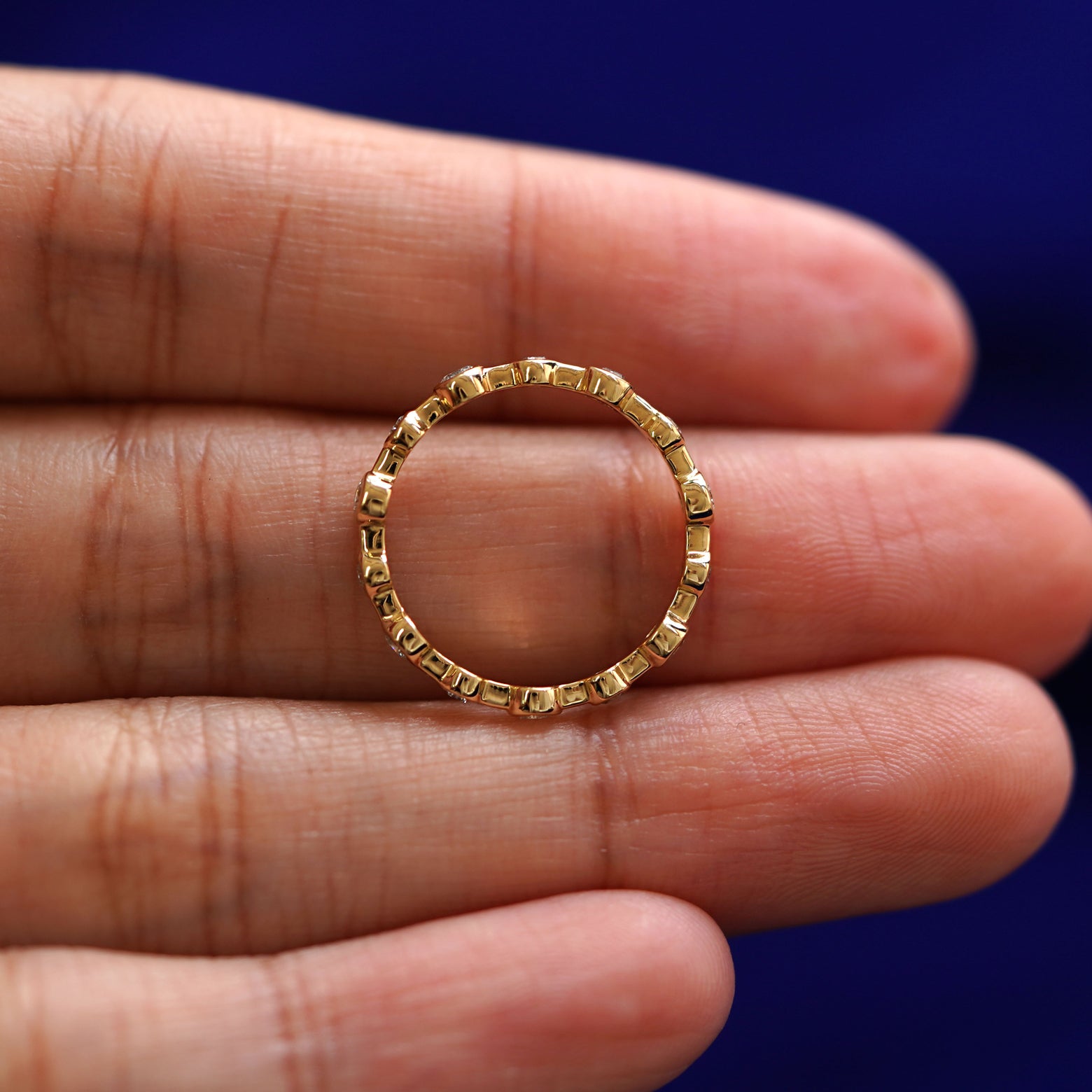 A yellow gold Infinity Diamond Ring in a model's hand showing the thickness of the band