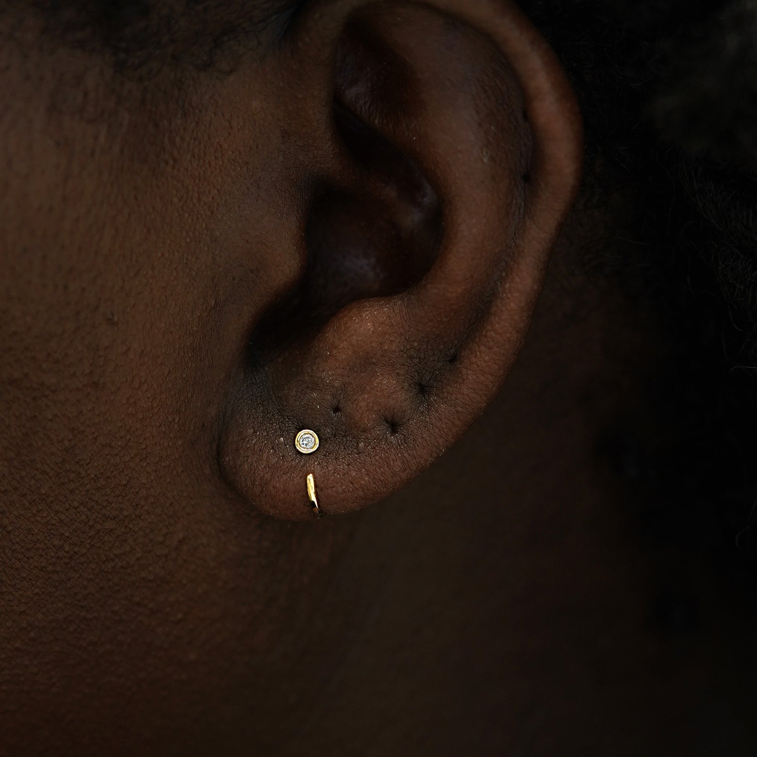 A model's ear wearing a 14k gold Diamond Open Hoop Earring