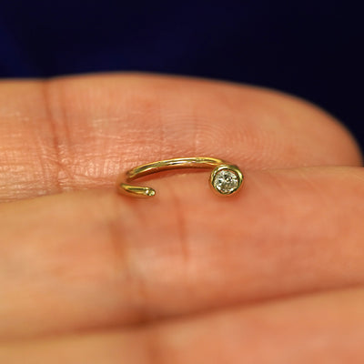 A 14k yellow gold Diamond Open Hoop resting on a models fingertip to show the open part of the earring