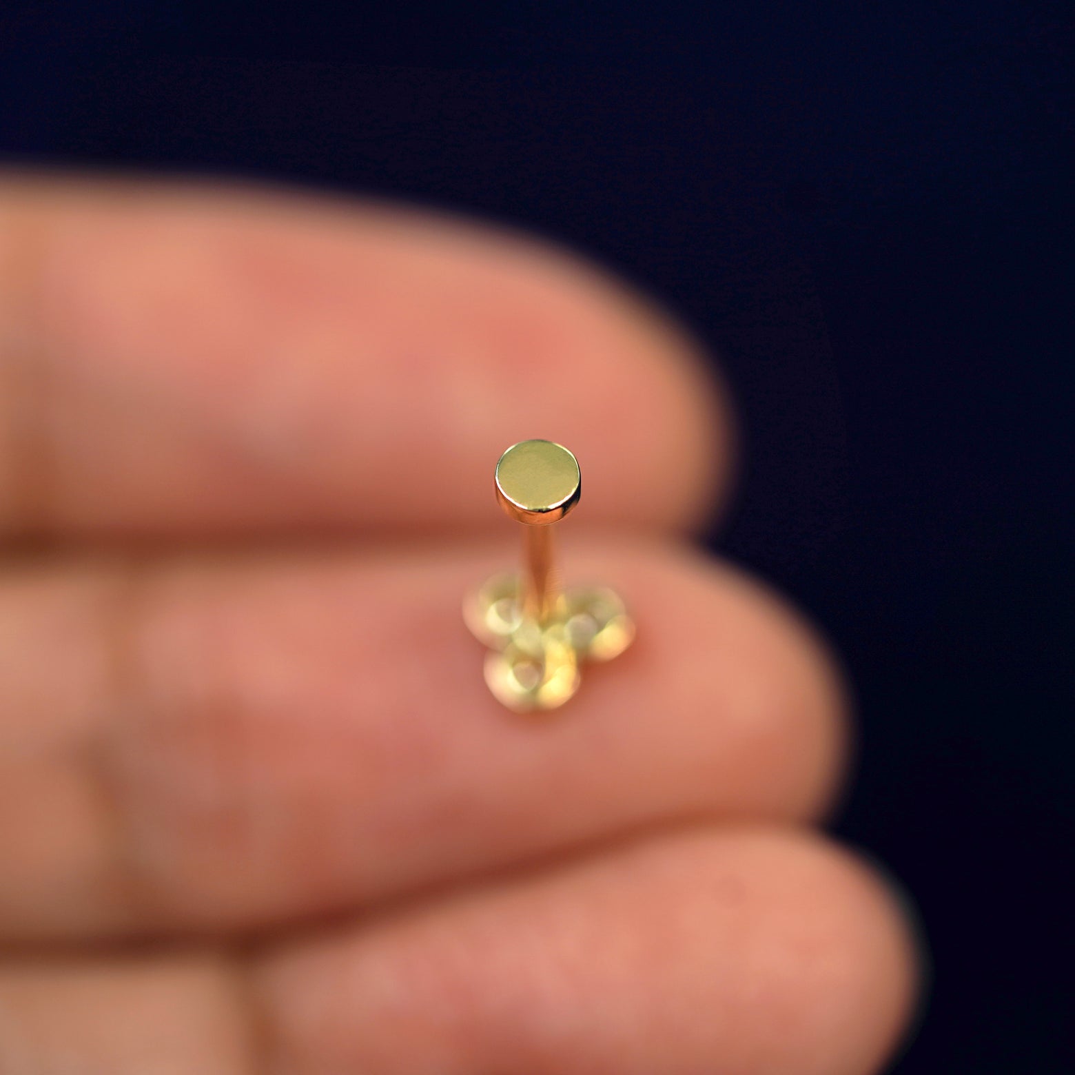 A Diamond Trio Flatback laying face down on a model's finger tip to show the flatback