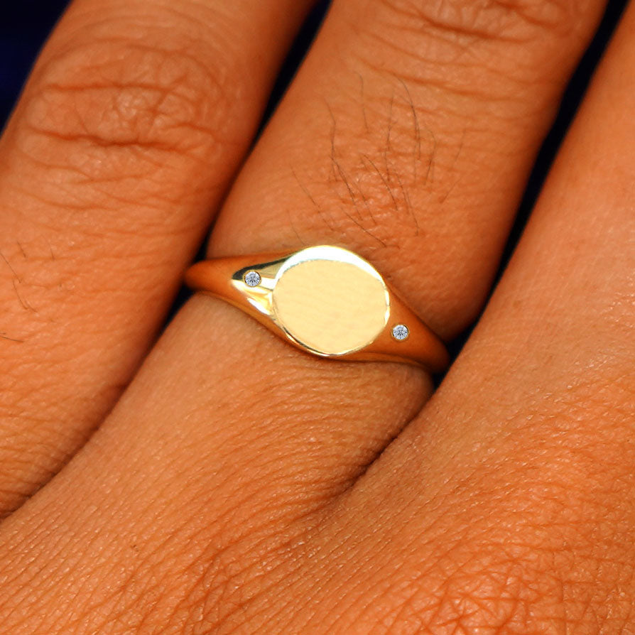 Close up view of a model's fingers wearing a 14k yellow gold Diamond Signet Ring