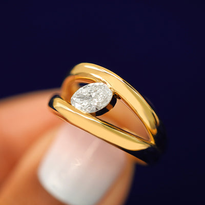 A model holding a Oval Lab Diamond Tension Ring tilted to show the side of the band