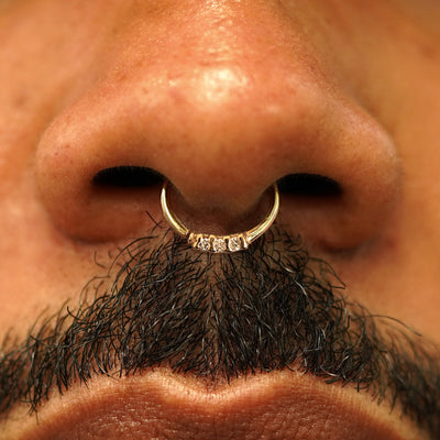 Close up view of a model's nose wearing a 14k yellow gold 3 Diamond Septum