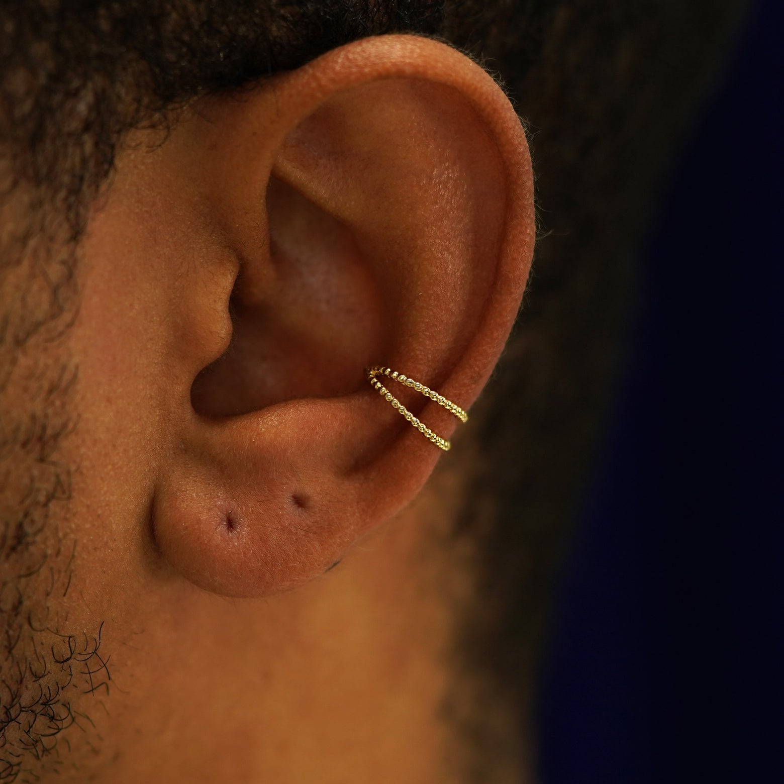 Close up view of a model's ear wearing a 14k yellow gold Bead Cuff