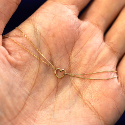 A yellow gold Heart Anklet draped on a model's palm