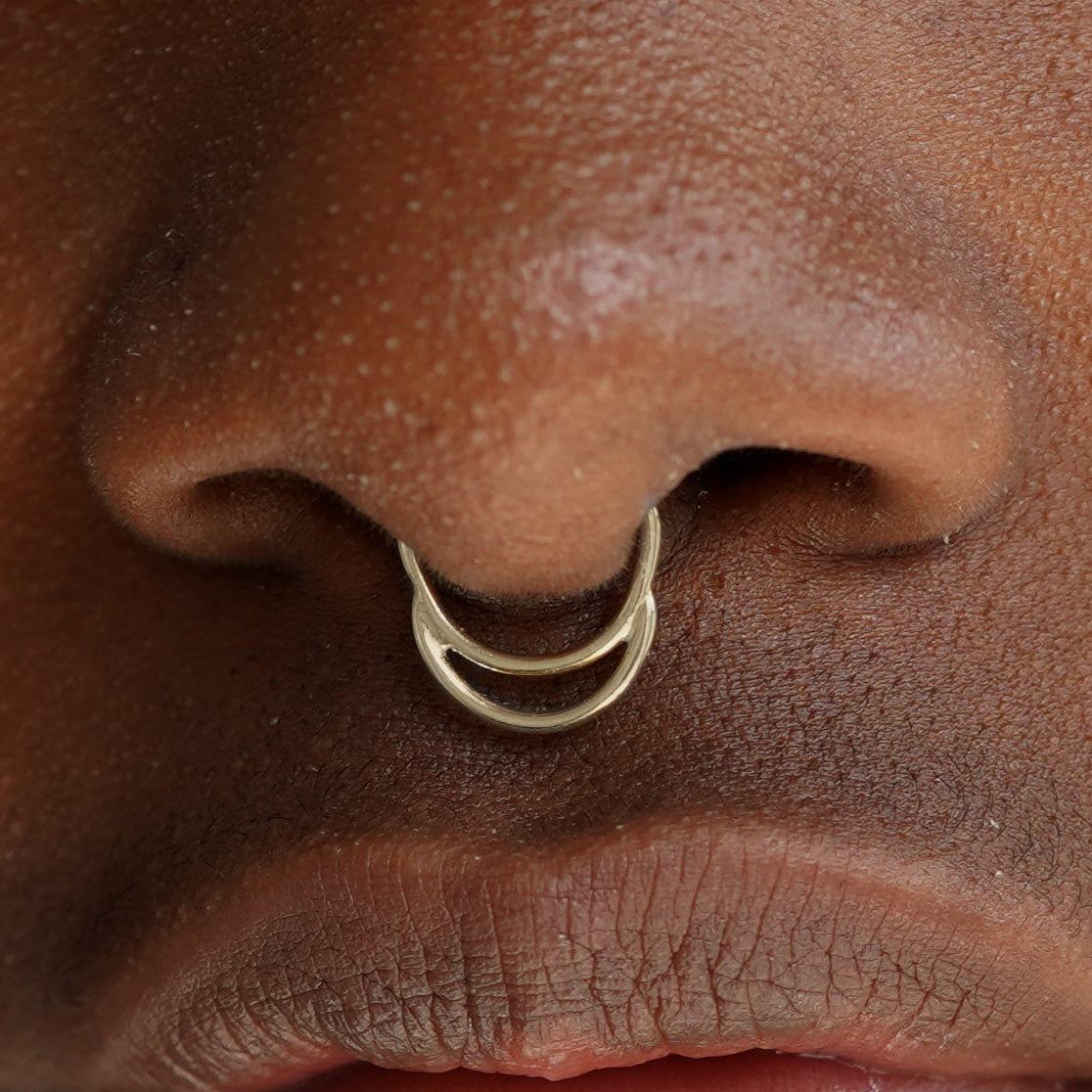Close up view of a model's face wearing a 14k solid champagne gold Double Circle Septum