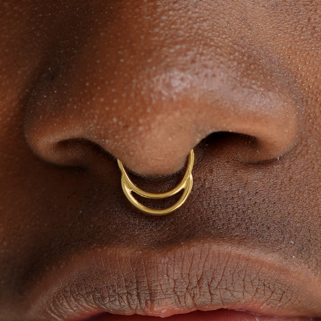 Close up view of a model's face wearing a 14k solid yellow gold Double Circle Septum