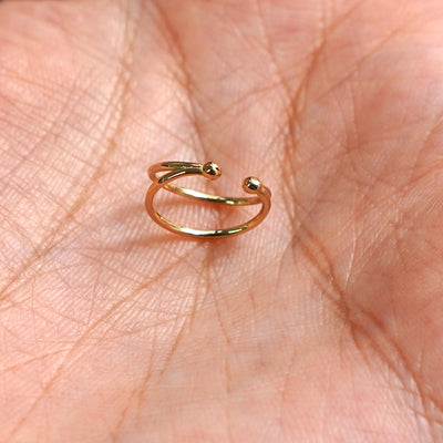 A solid yellow gold Double Cuff earring standing upright in a model's palm