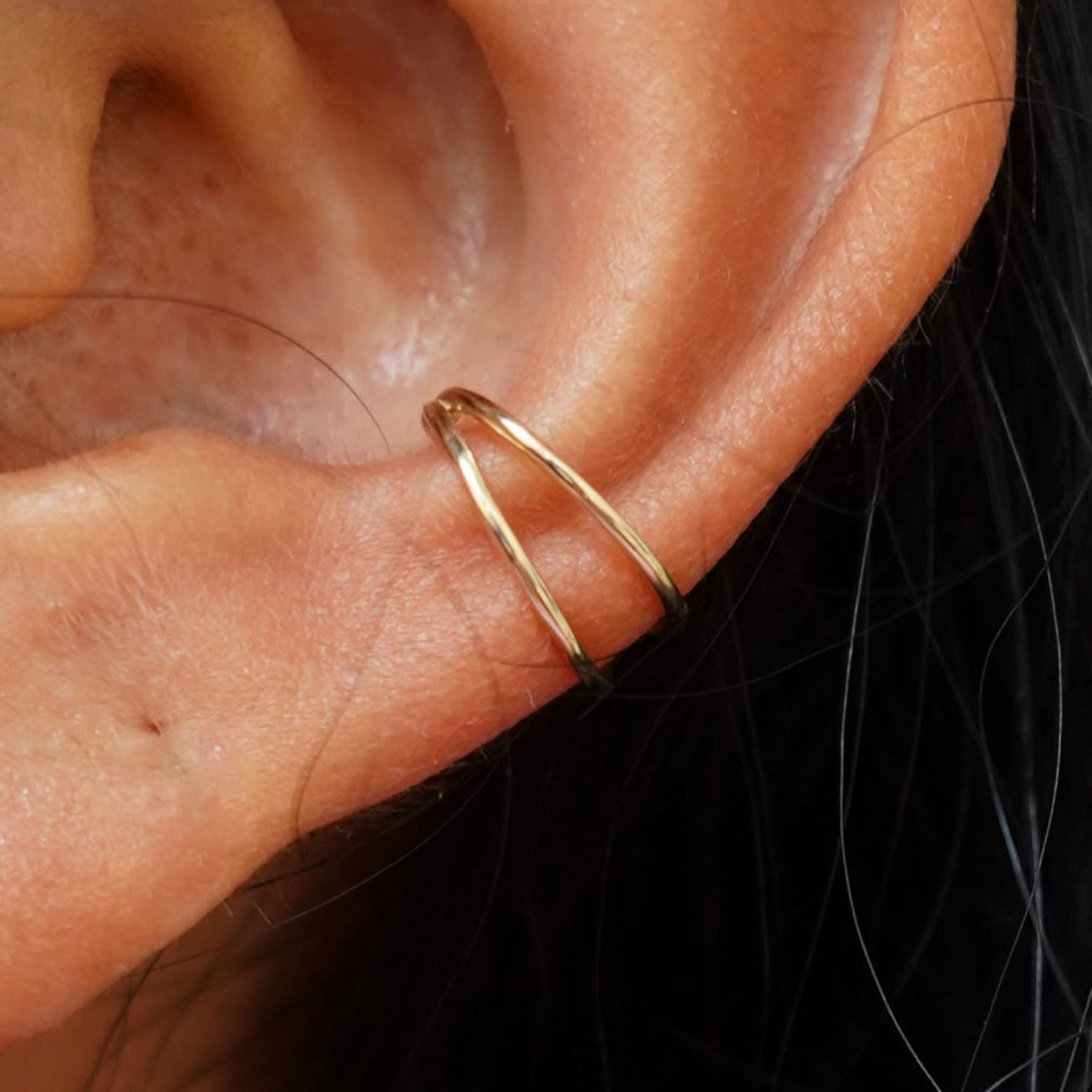 Close up view of a model's ear wearing a yellow gold Double Cuff