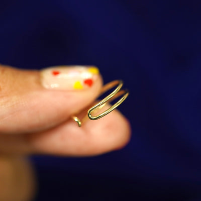 A model holding a yellow gold Double Line Ring in between two fingers to show the die of the ring