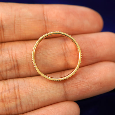 A yellow gold Edge Band in a model's hand showing the thickness of the band