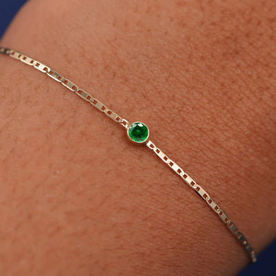 Close up view of a models wrist wearing 14k yellow gold Emerald Bracelet
