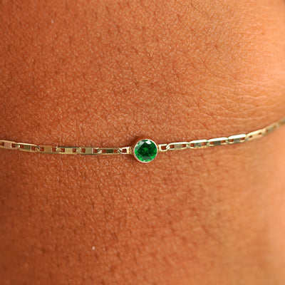 Close up view of a models wrist wearing 14k yellow gold Emerald Bracelet