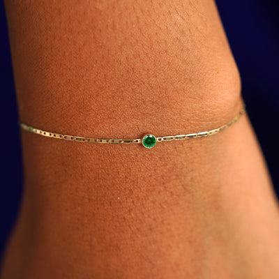 A model's wrist wearing a 14 karat yellow gold Emerald Bracelet