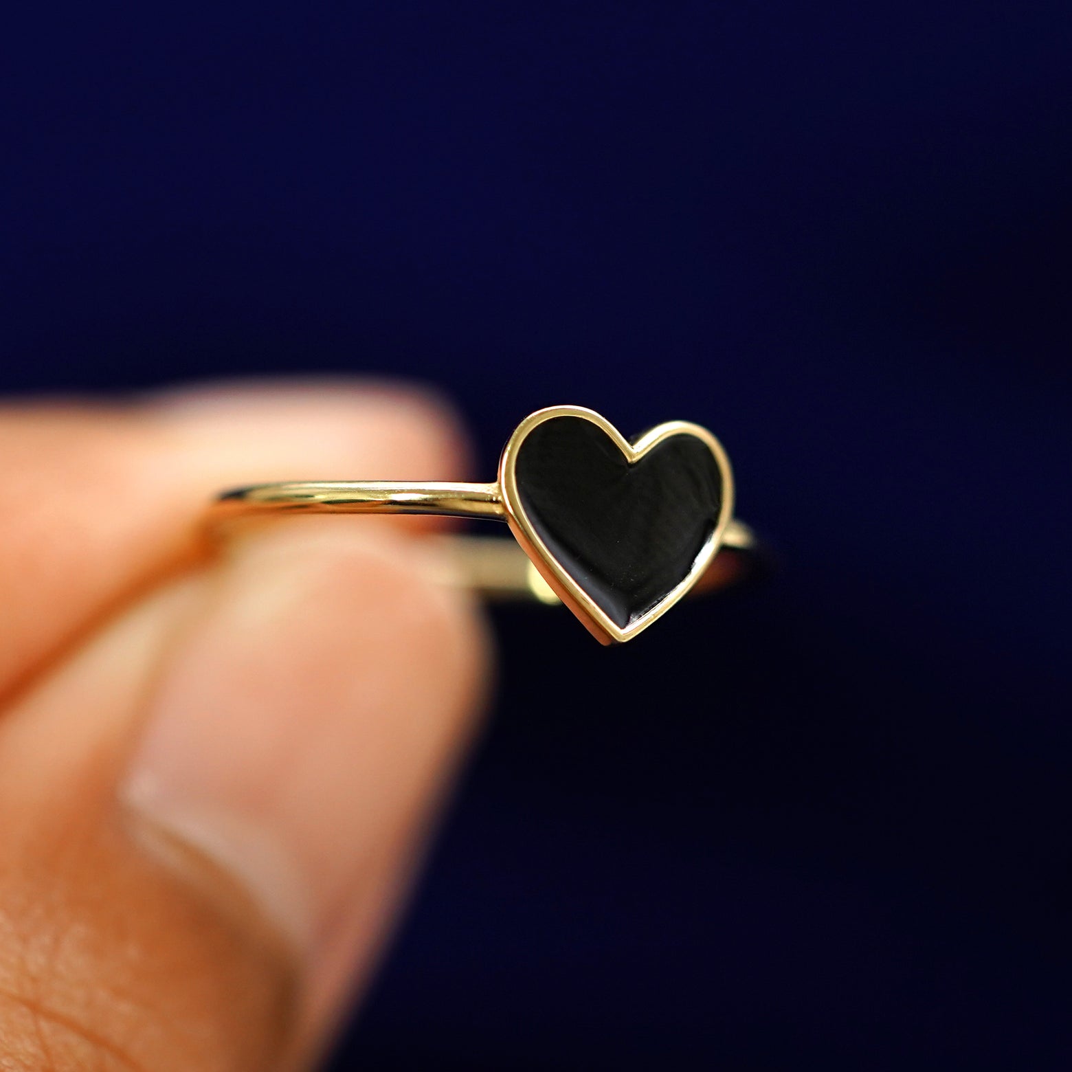 A model holding a Enamel Heart Ring tilted to show the side of the ring