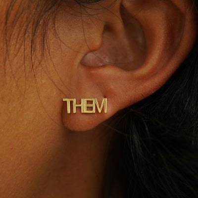 A model's ear wearing a solid 14k gold Them Earring