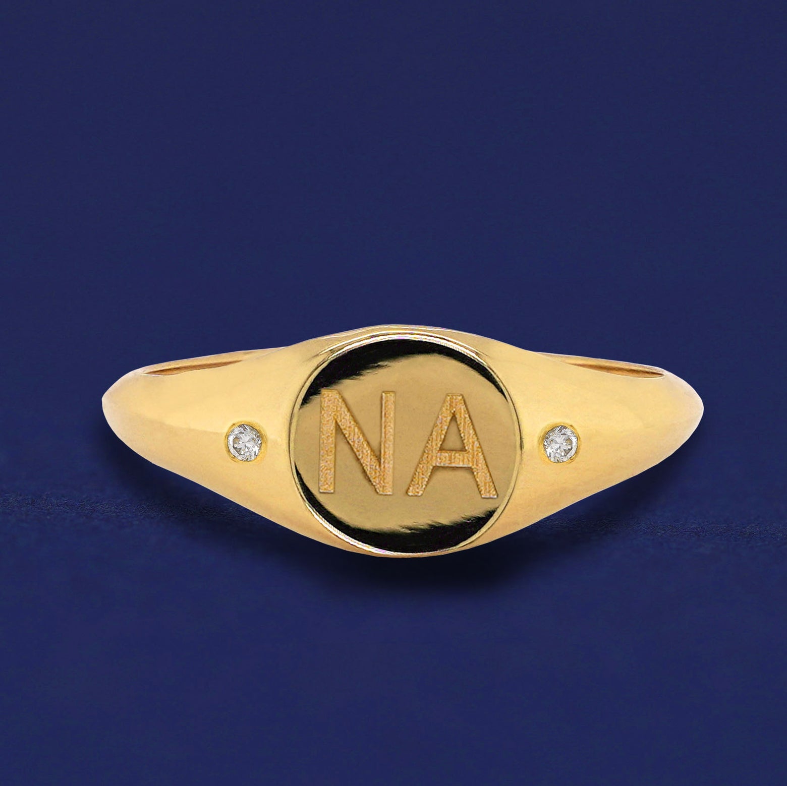 A solid yellow gold Diamond Signet Ring with the initials N A engraved on the top in a block font