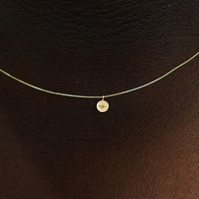 Close up view of a model's neck wearing a 14k yellow gold Star Disk Necklace