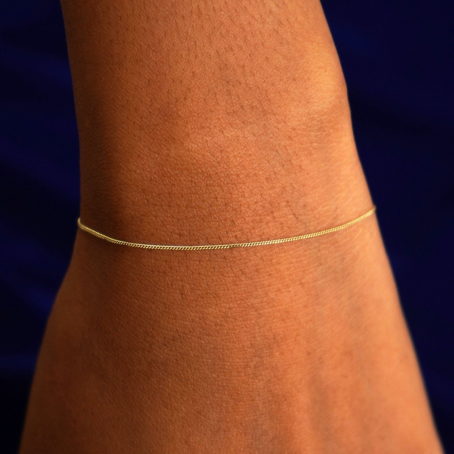 A model's wrist wearing a solid yellow gold Essential Bracelet