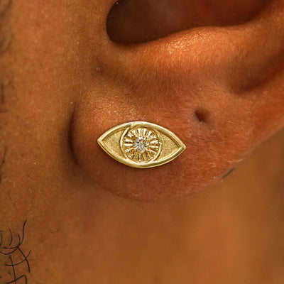 Close up view of a model's ear wearing a 14k gold Diamond Evil Eye Earring