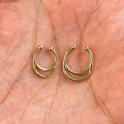 A model's palm holding two versions of the pierced Double Circle Septum showing the 8mm and 10mm sizes