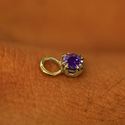 A solid yellow gold Amethyst Charm for earring resting on the back of a model's hand