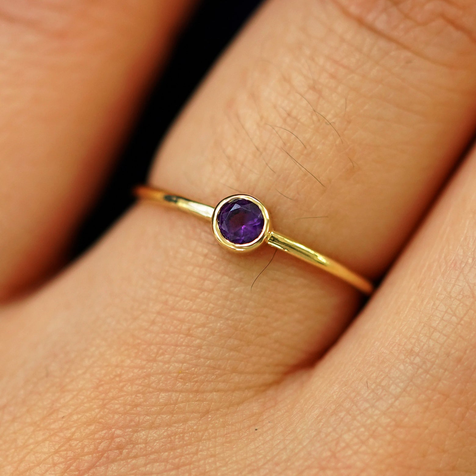 Close up view of a model's fingers wearing a 14k yellow gold Amethyst Ring