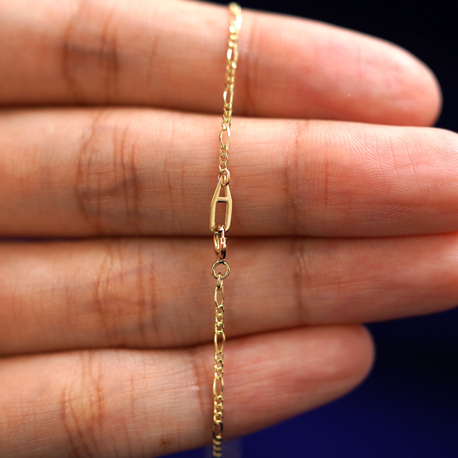 An Automic Gold AU spring ring clasp on a Figaro Chain