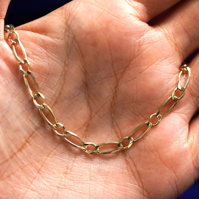 A yellow gold One to One Bracelet draped on a model's palm