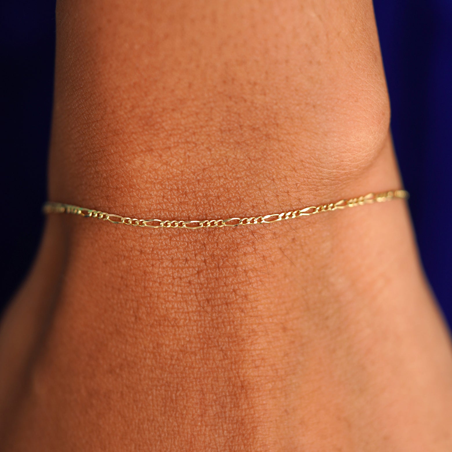 A model's wrist wearing a solid yellow gold Figaro Bracelet