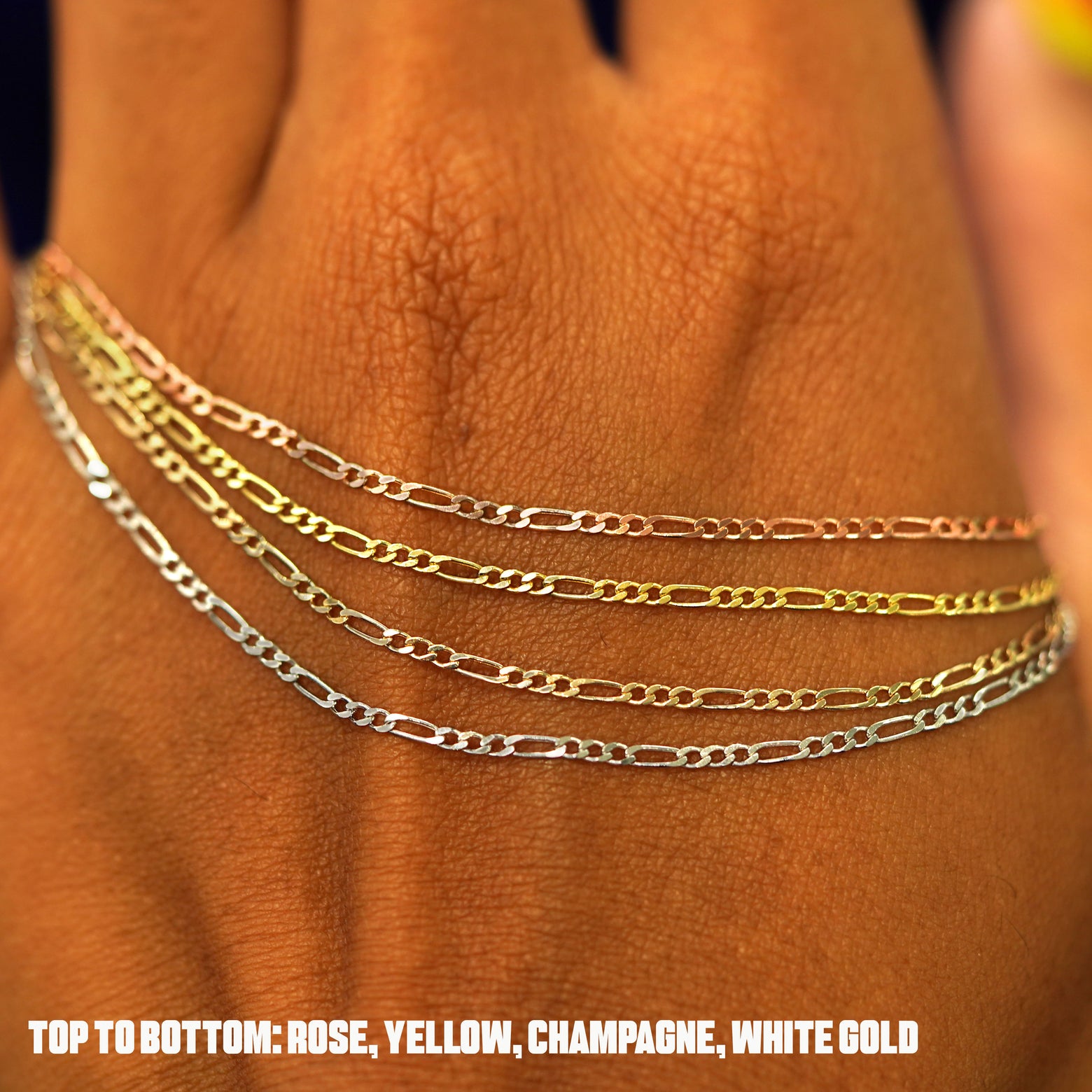 Four versions of the Figaro Bracelet in yellow, white, rose, and champagne gold draped on the back of a model's hand