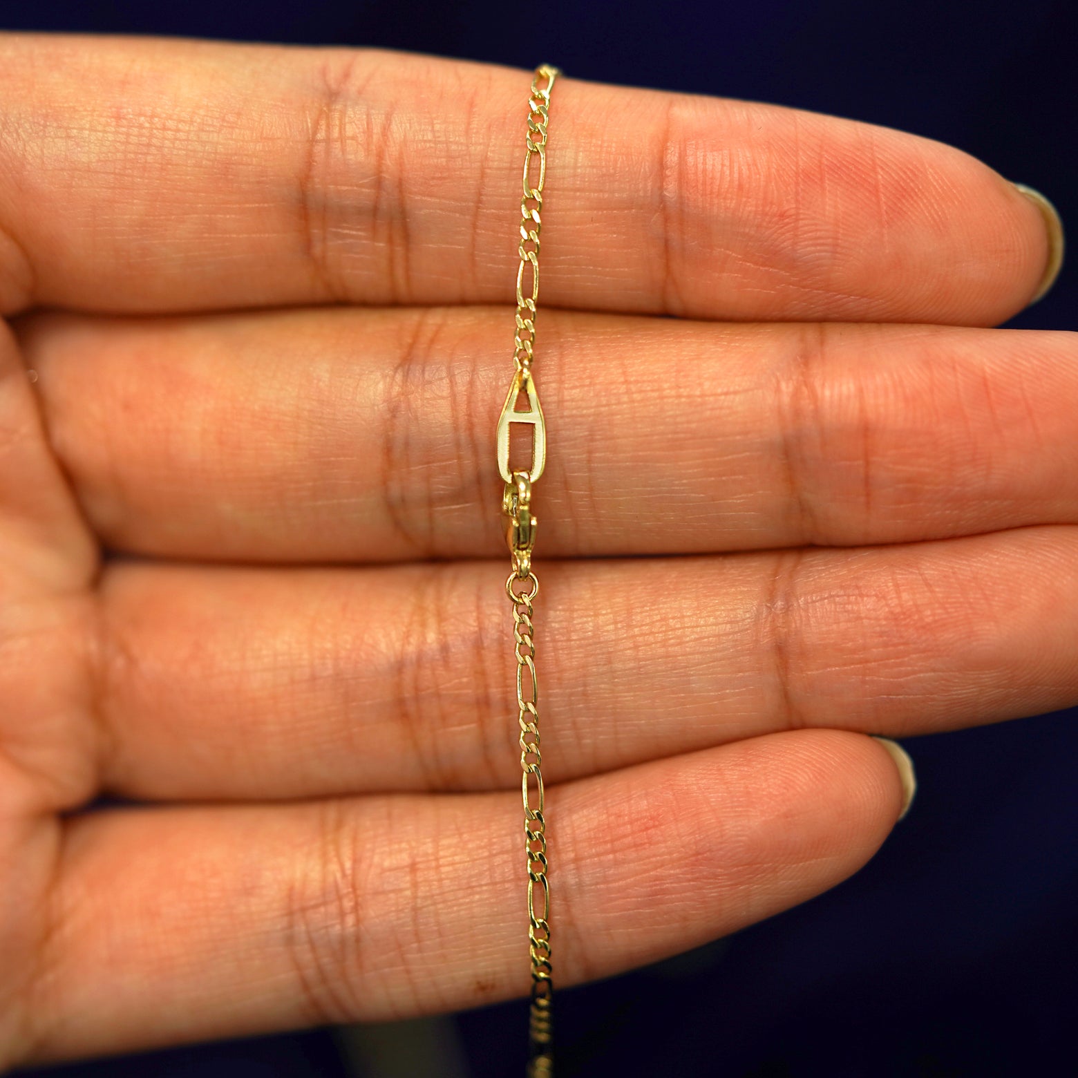 An Automic Gold AU lobster claw clasp on a Figaro  Chain