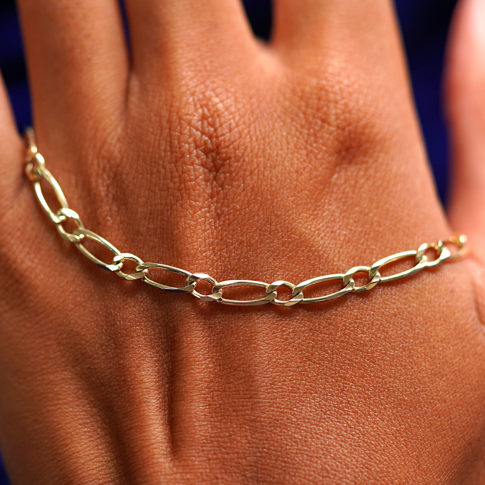 A solid gold One to One Chain resting on the back of a model's hand