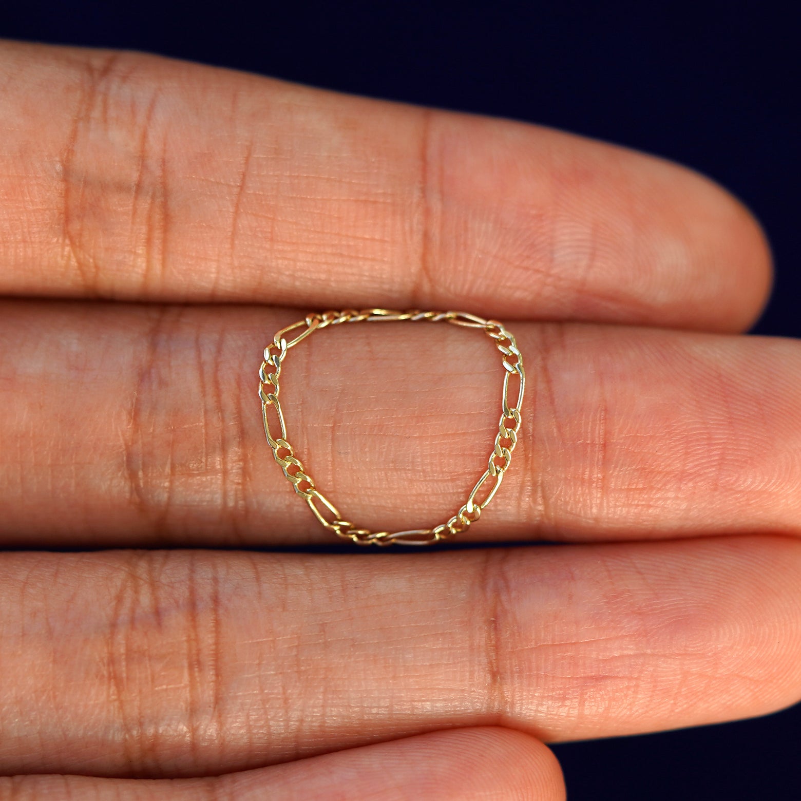 A solid 14k Figaro Chain Ring resting on a model's fingertips