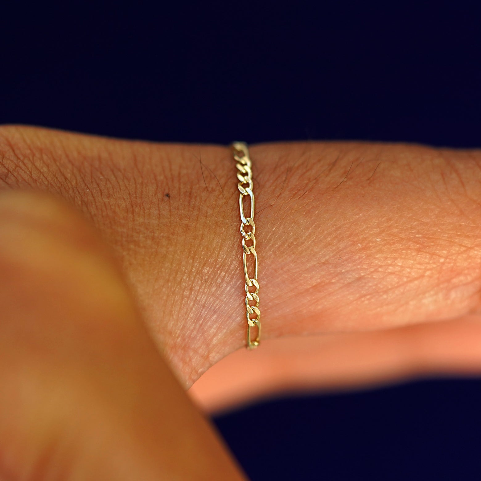 Side view of a model's finger wearing a yellow gold Figaro Ring