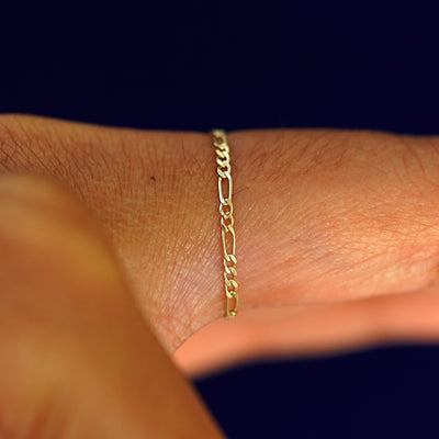 Side view of a model's finger wearing a yellow gold Figaro Ring