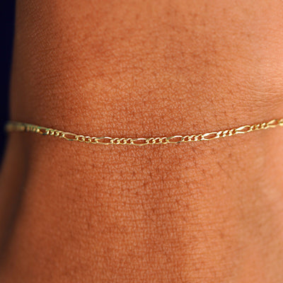 Close up view of a model's wrist wearing a solid yellow gold Figaro Bracelet